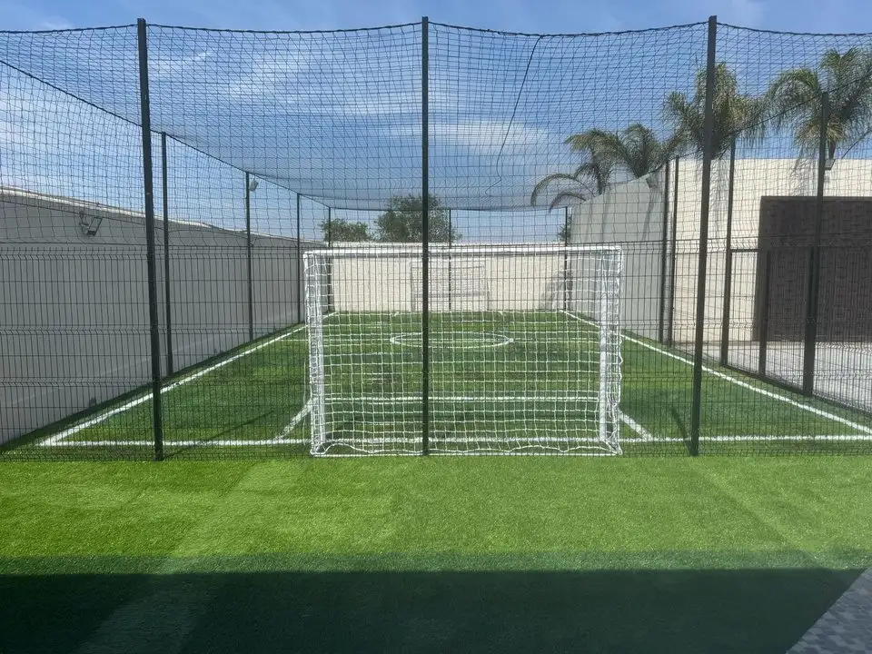 Cancha de pasto sintético con porterías y malla
