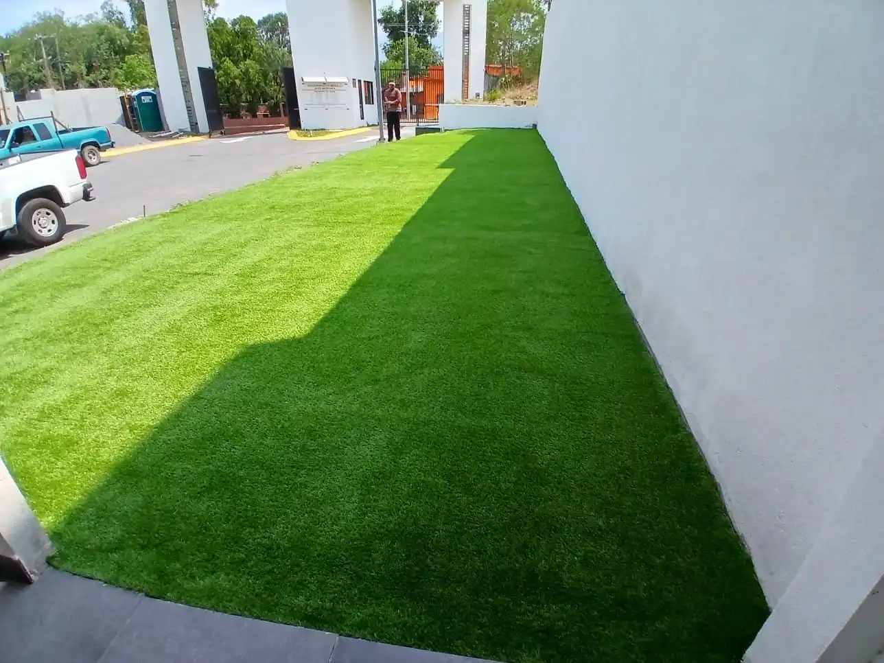 Pasto sintético residencial recién instalado junto a una pared blanca